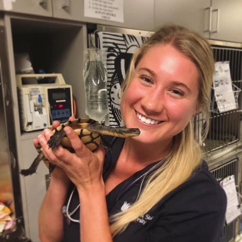 Sammy smiling at work in a veterinary clinic, holding a small animal